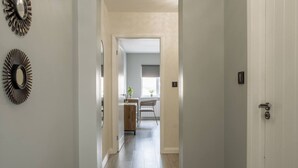 A hallway leading to a dining area with a wooden table and chairs, a potted plant, and a door on the right. - Stylish house with Backyard + 4 min walk to Beach (Great Yarmouth)
