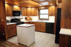Una cocina con gabinetes de madera, microondas, estufa, fregadero y lavavajillas.