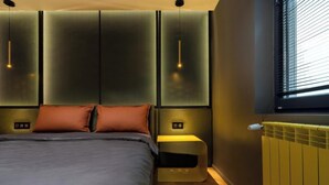 Una camera da letto moderna con un letto, due comodini, un riscaldatore a parete e una finestra con persiane.