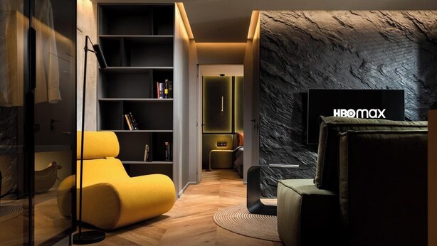 Un soggiorno moderno con un divano, una lampada da terra, una libreria e una televisione.