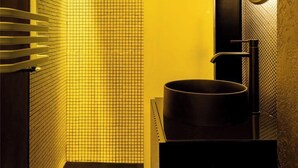 Un bagno moderno con parete piastrellata, lavandino nero e specchio.