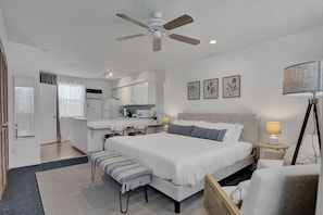 A bedroom with a large bed, a desk, and a ceiling fan.