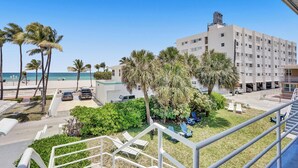 Ein Hotel mit Blick auf den Strand, Palmen und einen Parkplatz.