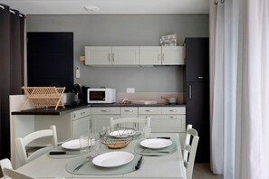 A compact kitchen with white cabinets, a microwave, and a dining area set for four.