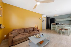 A living room with a sofa, a coffee table, and a dining area with a table and chairs.