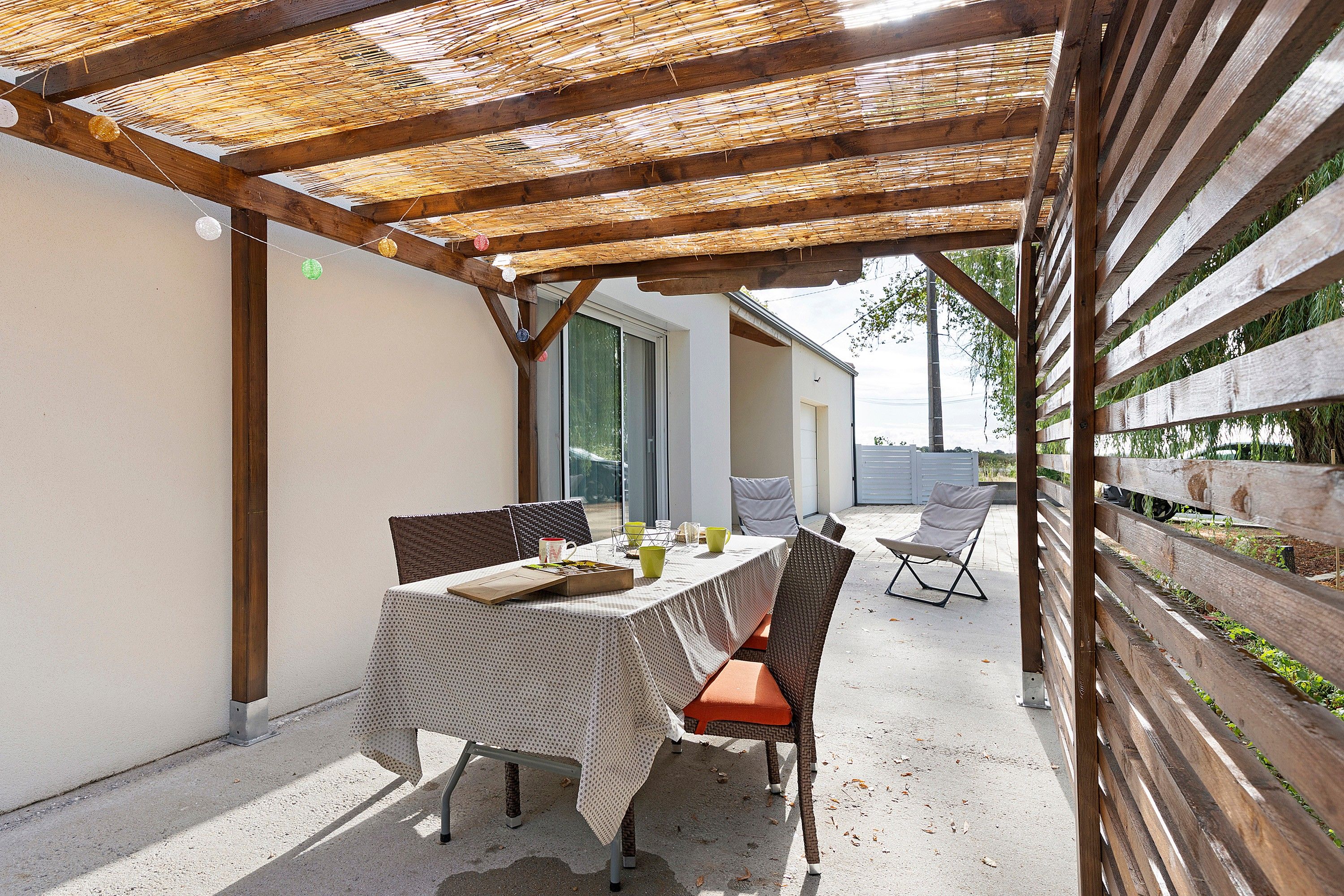 En uteplats med ett bord och stolar, en pergola ovanför och utsikt över det omgivande området.