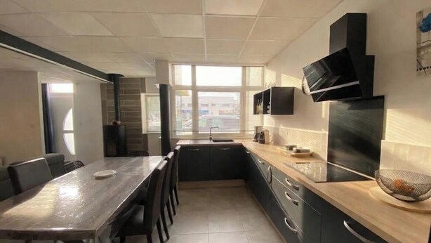 A modern kitchen with a dining area, large windows, and a flat-screen TV mounted above the counter. - Charming house in the heart of L'Aiguillon-sur-mer - 8 people (L'Aiguillon-la-Presqu'île)