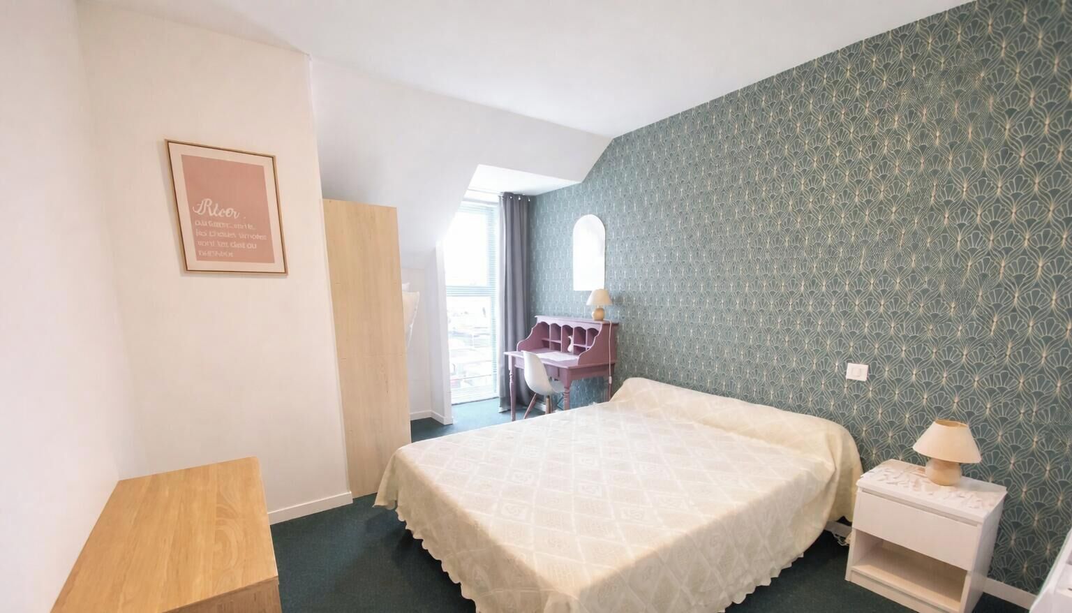 Une chambre à coucher avec un lit, un bureau, une chaise, une table de chevet et une fenêtre.