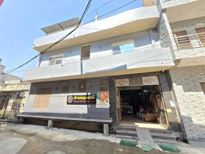 A two-story building with a signboard, a staircase leading to the entrance, and a small outdoor seating area. - Hotel O Prem Mandi (Mathura)