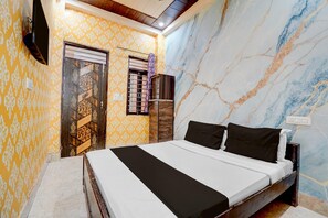 A bedroom with a bed, a wardrobe, a television, and a patterned wall. - Hotel O Prem Mandir (Mathura)