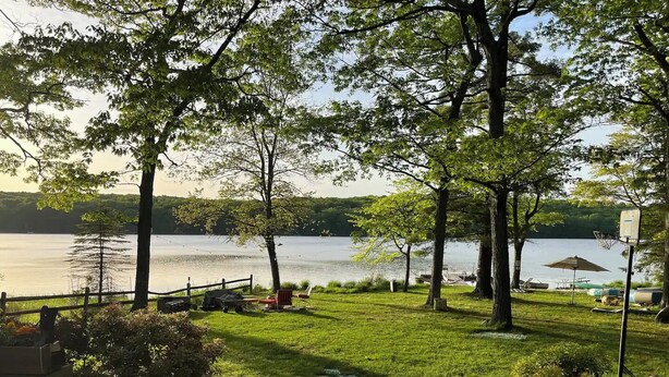 Terraza junto al lago con canasta de baloncesto, parilla y mesa de picnic.