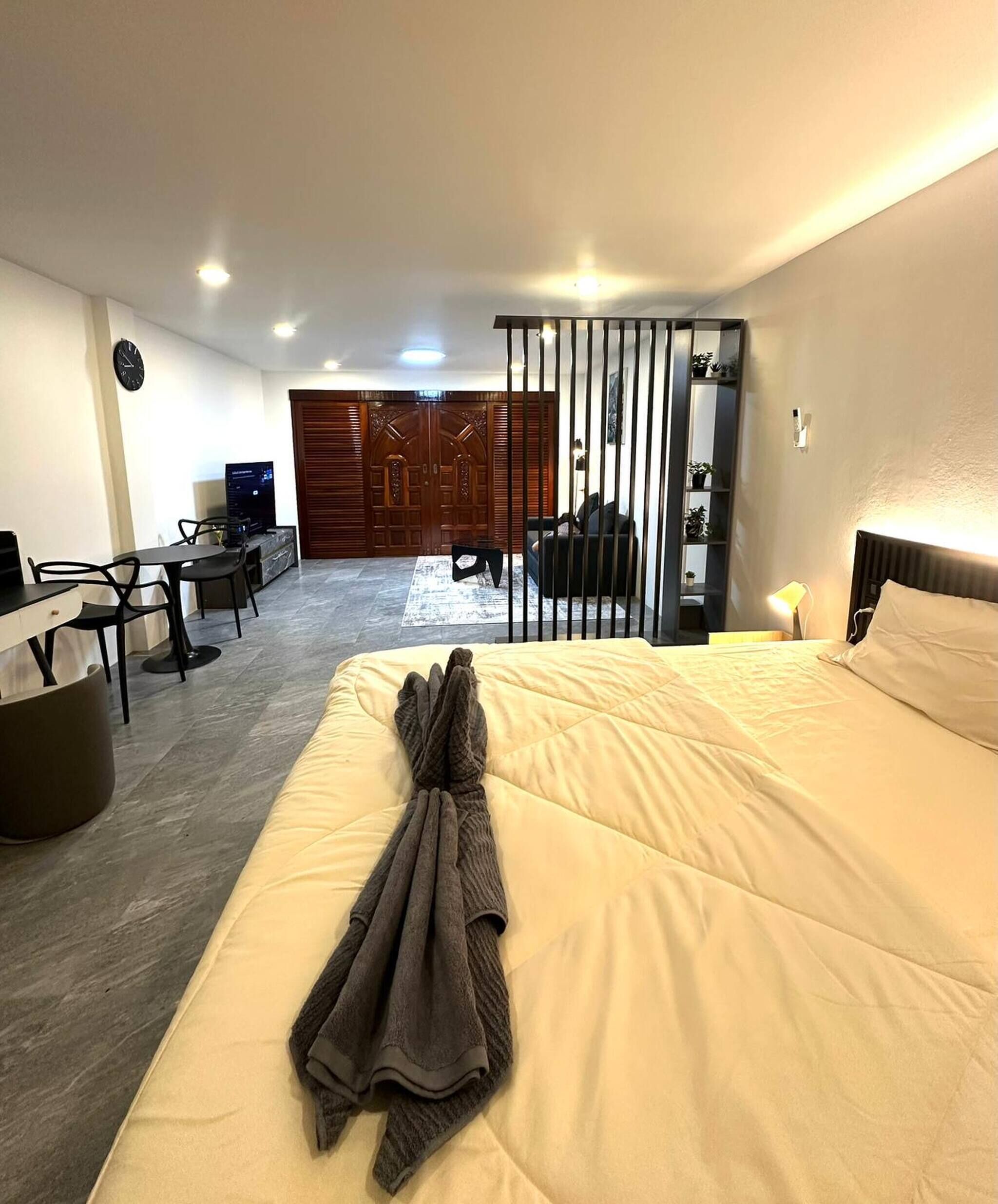 A hotel room with a bed, a desk with a chair, a TV, and a wardrobe.