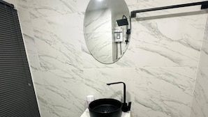 A bathroom with a marble wall, a round mirror, a black sink, and a toilet. - Smart Studio Appartment Near Old Town Phuket (Phuket)