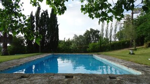 A rectangular swimming pool with stone edges, surrounded by grass and trees. - Holiday Home 'Casa Das Figueiras' with Private Pool, Private Terrace and Wi-Fi (Pinhal Novo)