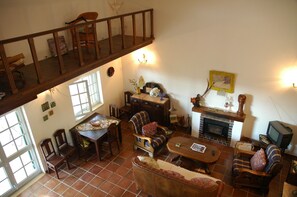 A spacious living room with a high ceiling, a fireplace, a television, and a dining area. - Holiday Home 'Casa Das Figueiras' with Private Pool, Private Terrace and Wi-Fi (Pinhal Novo)