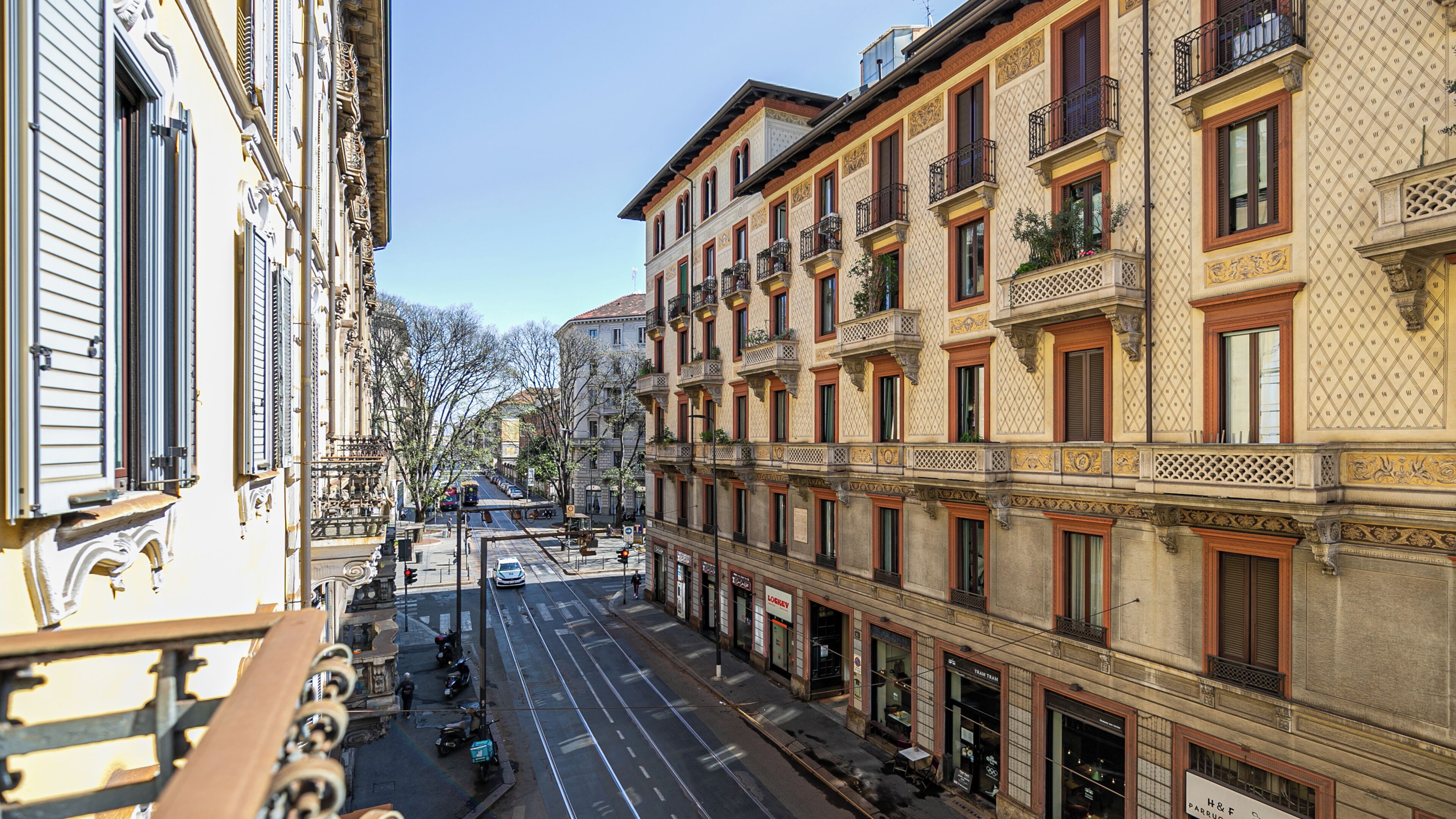 A street view with buildings featuring ornate facades and balconies.