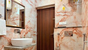 Ein Badezimmer mit Marmorwaschbecken, Toilette, Dusche und Holztür.