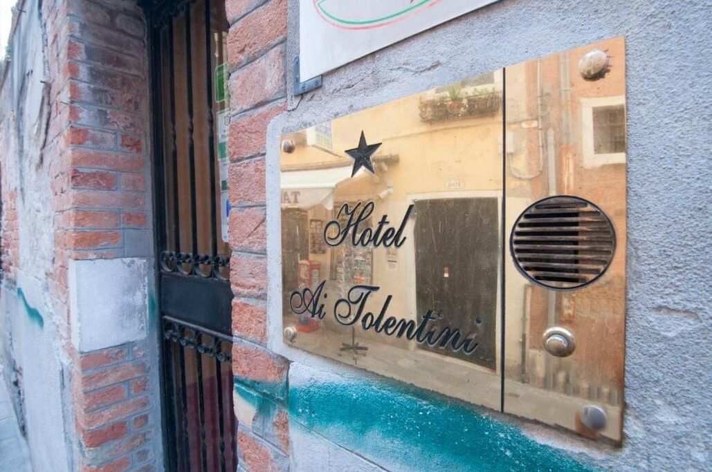 Ein Hotelschild mit dem Schriftzug 'Hotel Ai Tolentini' an einer Wand.