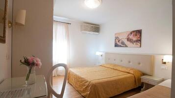 A hotel room with a bed, bedside table, lamp, and a painting on the wall.