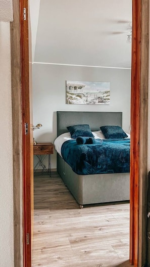 Ein Schlafzimmer mit Bett, Nachttisch, Lampe und einem Gemälde an der Wand.