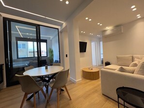 A modern interior with a round table, chairs, a sofa, and a TV. - BlueMotion - CruiseNest Double (Piraeus)