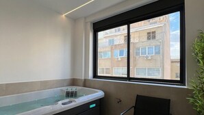 Een moderne badkamer met een badkuip, een raam en een stoel.