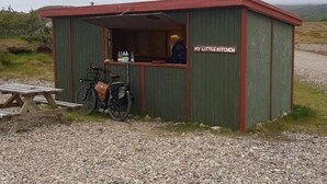 A small, green and red structure labeled 'MY LITTLE KITCHEN' with a bicycle and picnic table outside. - Stafafell Nature Park Camping (Stafafell)