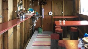 A wooden interior with a kitchen area, bar stools, and a counter. - Stafafell Nature Park Camping (Stafafell)