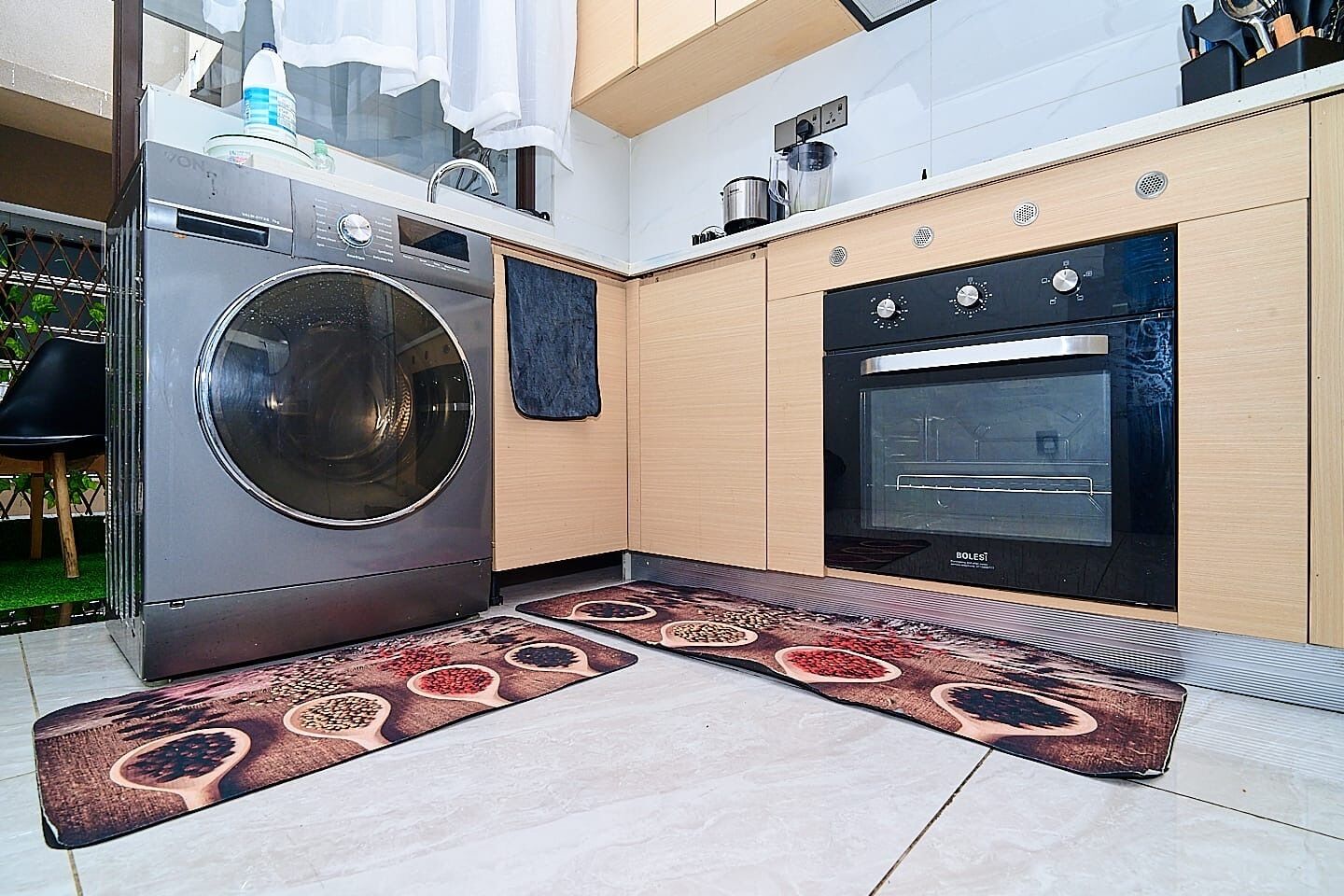 Una cucina moderna con lavatrice integrata, forno e un tappeto dal disegno originale.