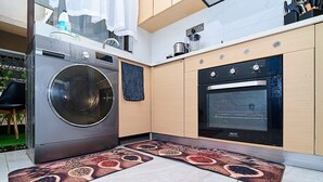 Moderni keittiö, jossa on sisäänrakennettu pesukone, uuni ja ainutlaatuinen kuvioitu matto.