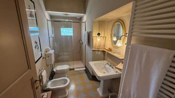 A compact bathroom with a toilet, bidet, sink, and shower.