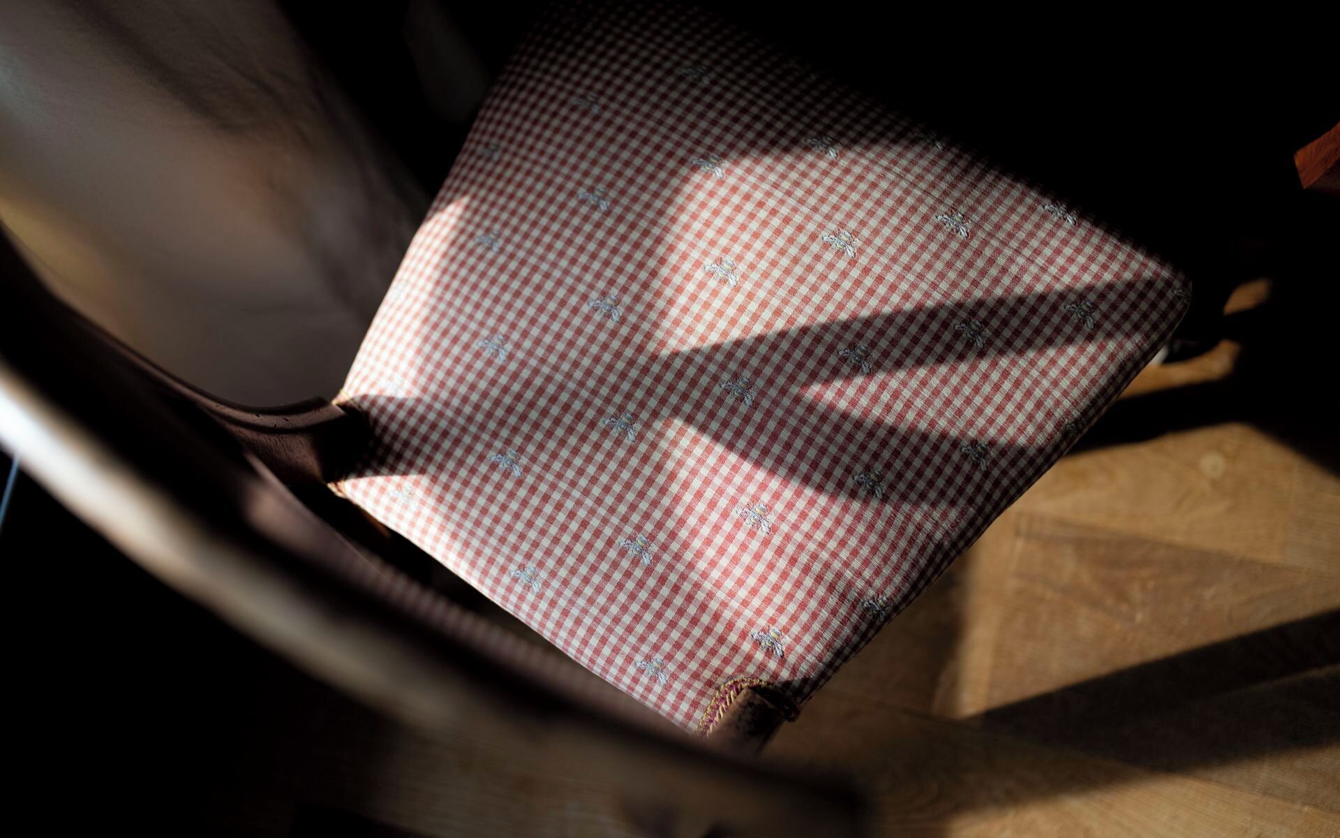 Ein Detailaufnahme eines karierten Stoffes mit Muster, vermutlich Teil einer Sitzfläche oder Polsterung.