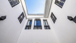 A building with a skylight, three windows with black iron grilles, and a white facade. - Incredible RIAD in the heart of the Medina (Marrakech)
