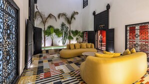 A living room with a sofa, a coffee table, and a patterned floor. - Incredible RIAD in the heart of the Medina (Marrakech)