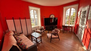 A living room with a sofa, chairs, a TV, and a dining table. - House with Balcony and Sea View in La Richardais (La Richardais)
