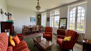 A spacious room with a large window, a chandelier, a wooden coffee table, and striped sofas. - House with Balcony and Sea View in La Richardais (La Richardais)
