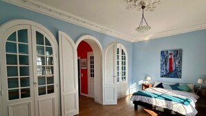A bedroom with a bed, a chair, a painting, and a chandelier. - House with Balcony and Sea View in La Richardais (La Richardais)
