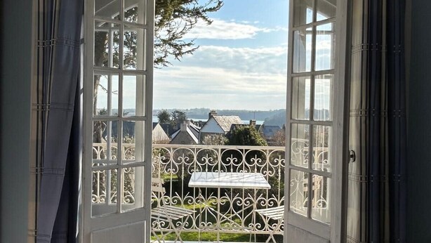 An open doorway leading to a balcony with a view of a town and a metal fence. - House with Balcony and Sea View in La Richardais (La Richardais)