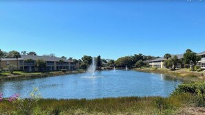 A pond with fountains, surrounded by buildings with a flat roof and large windows. - Update and Immaculate, 2 beds 2 baths end unit. On Imperial Golf Course (Naples)