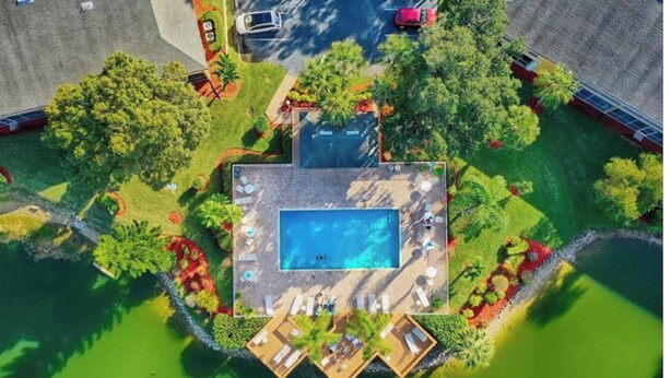 An aerial view of a property with a swimming pool, multiple decks, and lush landscaping. - Update and Immaculate, 2 beds 2 baths end unit. On Imperial Golf Course (Naples)