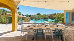 An outdoor dining area with a table set for six, surrounded by chairs, under a canopy. - Maison Des Arches Mérindol, spacious and bright. 6 bedrooms, private pool. (Mérindol)