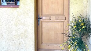 A wooden door with a sign above it, a small window with a plant, and a potted plant beside the door. - Maison Des Arches Mérindol, spacious and bright. 6 bedrooms, private pool. (Mérindol)
