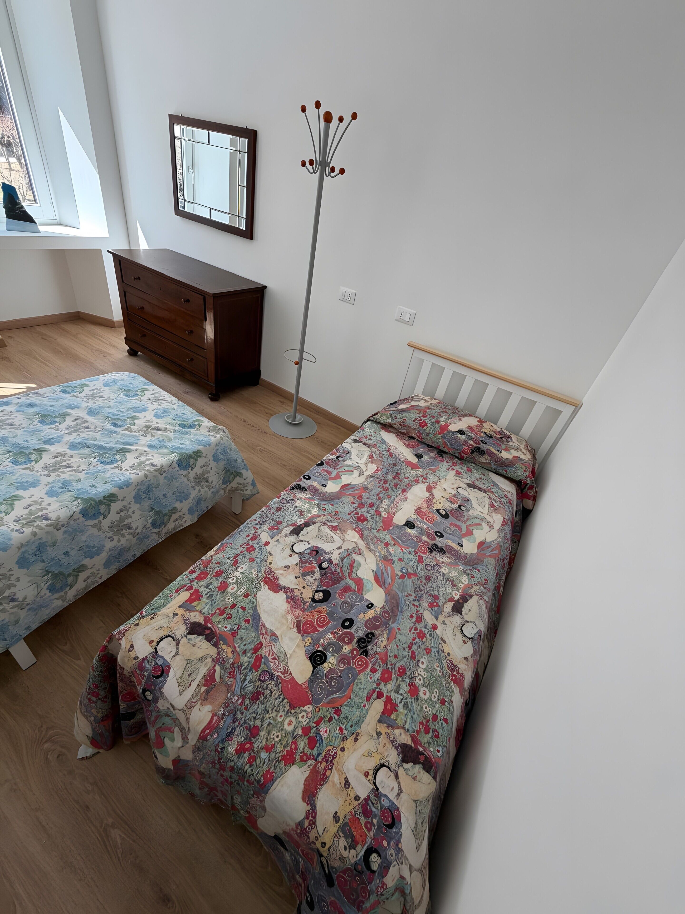 Ein Schlafzimmer mit zwei Betten, einem Schminktisch, einem Kleiderständer und einem Fenster mit Blick.