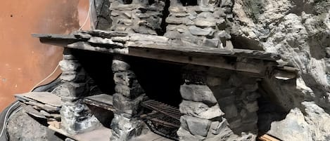 Una estructura de piedra con una rejilla de metal y tablones de madera.