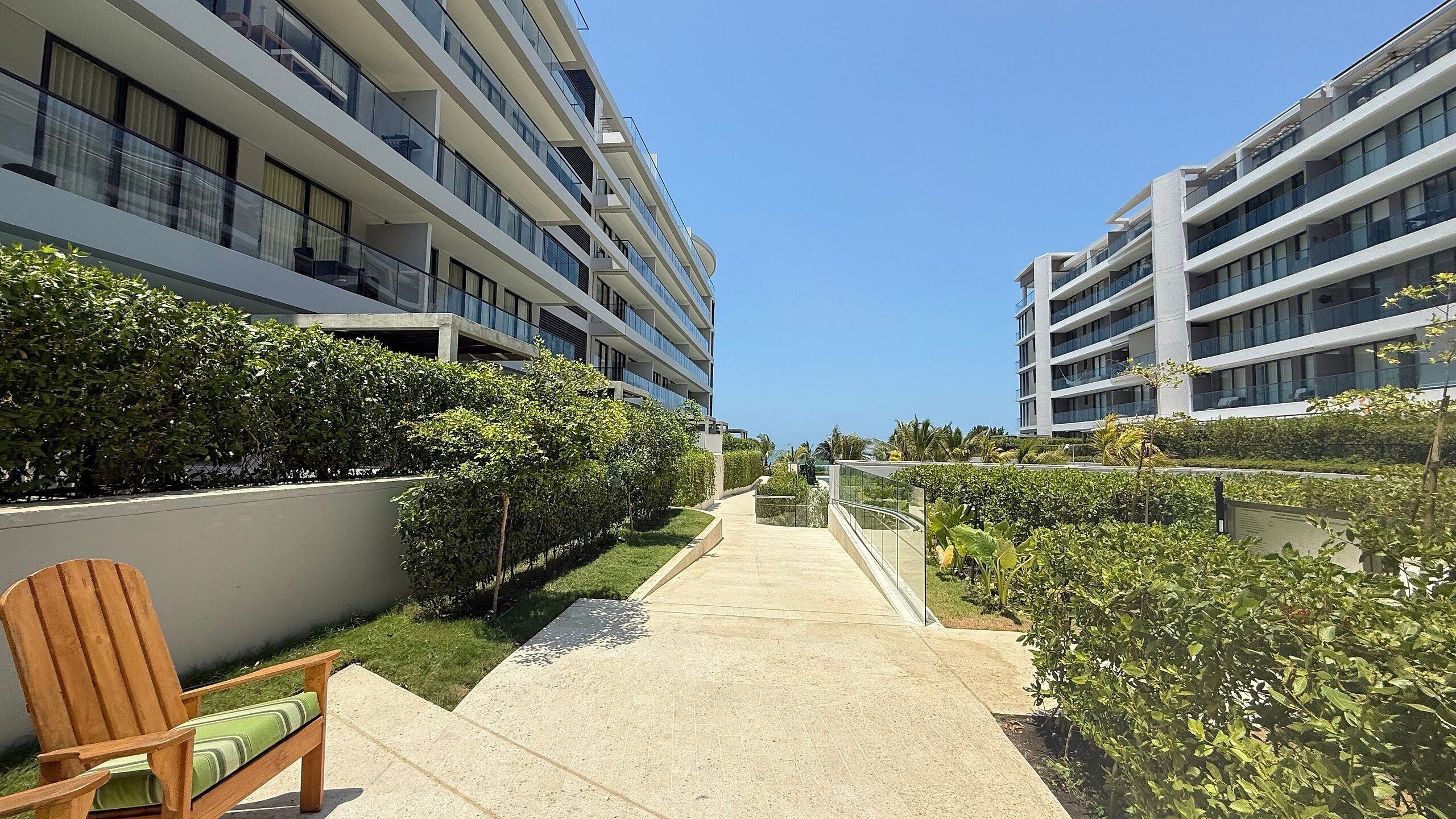 A modern hotel with multiple floors, a central pathway, and well-maintained greenery.