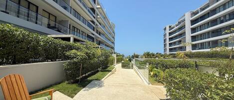 A modern hotel with multiple floors, a central pathway, and well-maintained greenery.