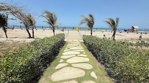 A pathway leading to a beach with palm trees and a clear sky. - APTO MORROS KAI CON SALIDA AL MAR  (Cartagena)