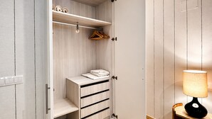 Um closet espaçoso com prateleiras de madeira, um cabideiro e uma cadeira dobrável.