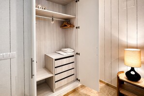 A walk-in closet with wooden shelves, a hanging rack, and a foldable chair. - Stylish and Spacious Studio in Seville Heart San Leandro II (Seville)