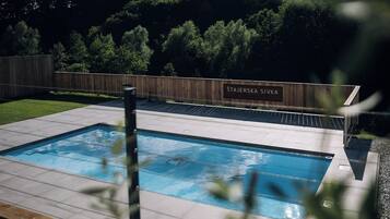 A swimming pool with a wooden fence and a sign that reads 'ŠTAJERSKA SIVKA RESORT 5.'